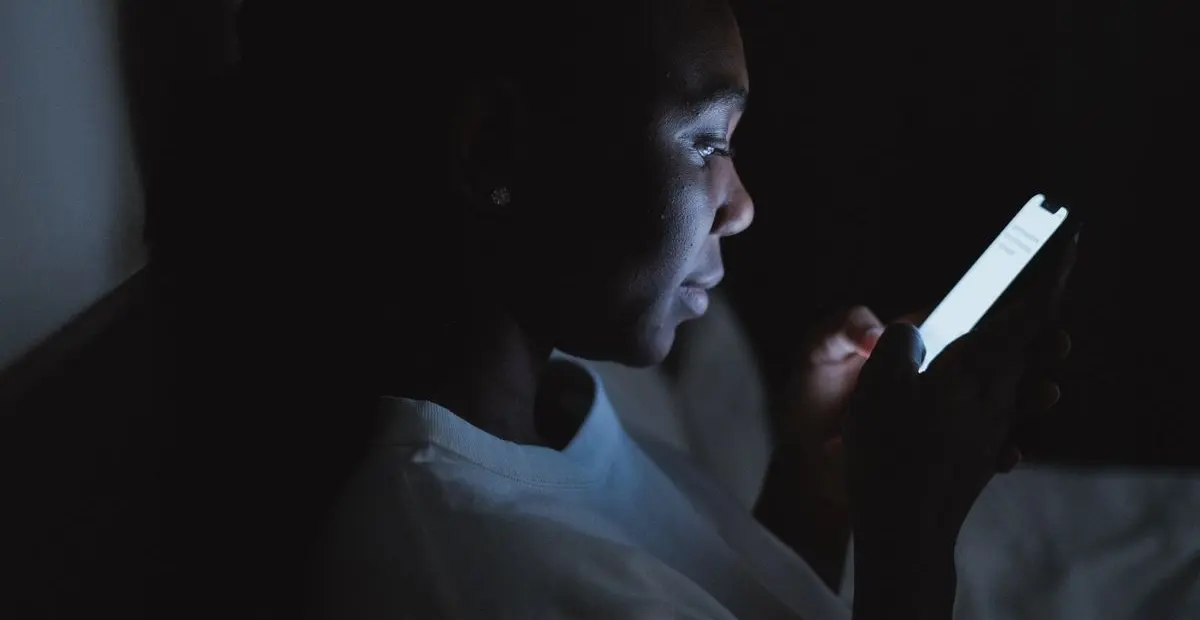 A person reading a business website on their phone late at night.